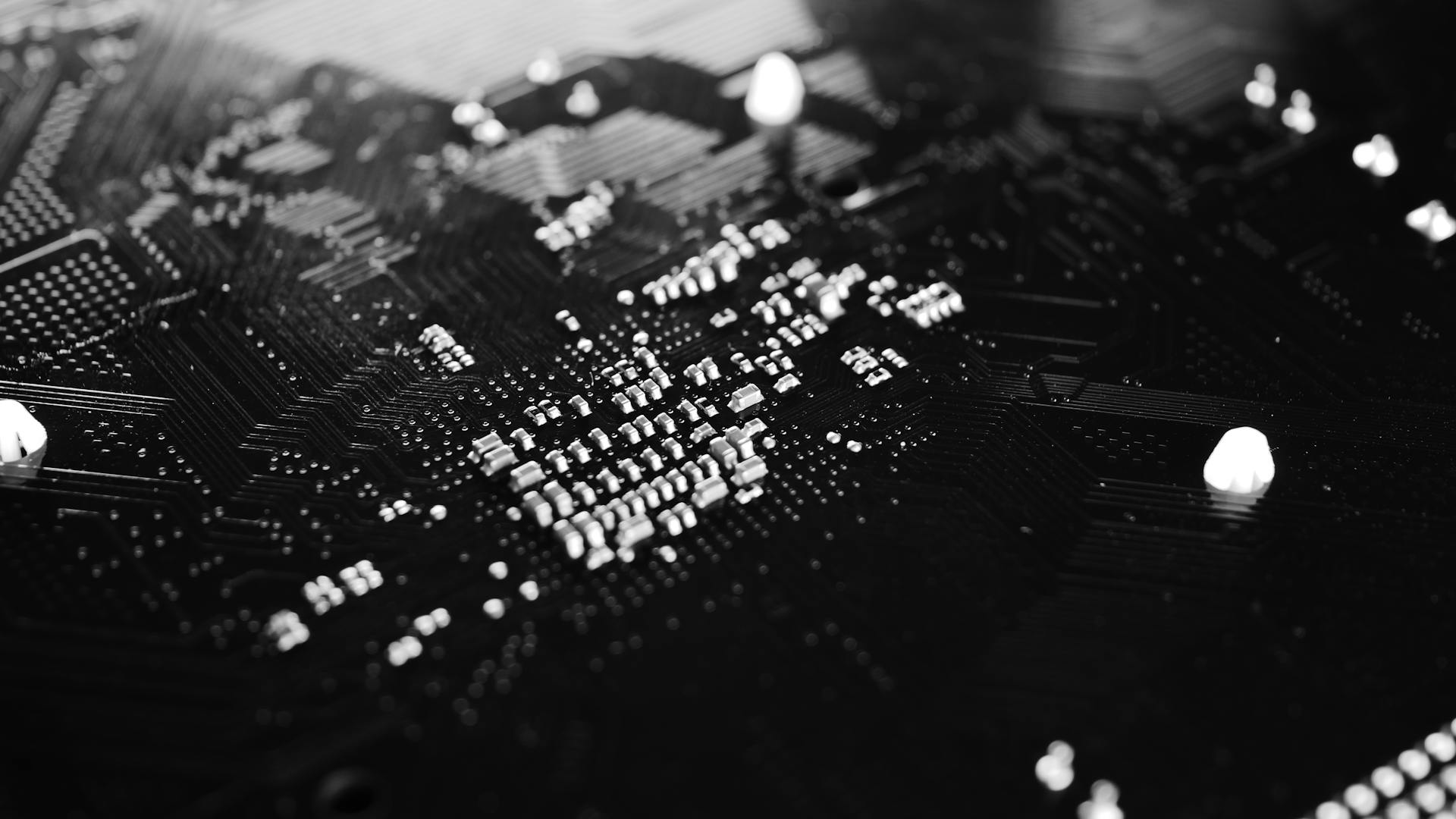 Black and white close-up of a circuit board with intricate patterns and components.