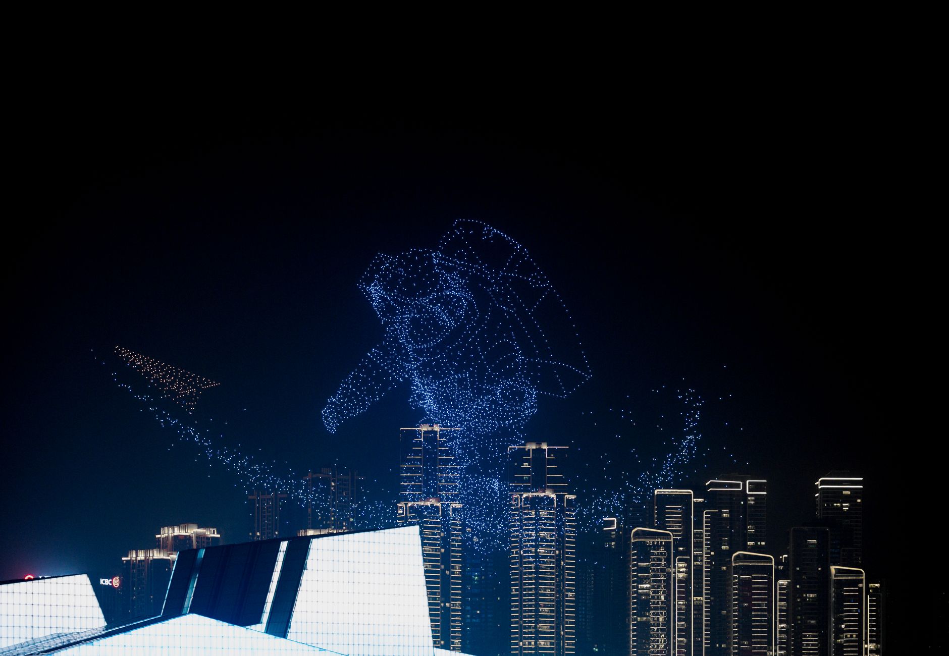 Breathtaking drone light show forming astronaut shape above city skyline, showcasing innovation.
