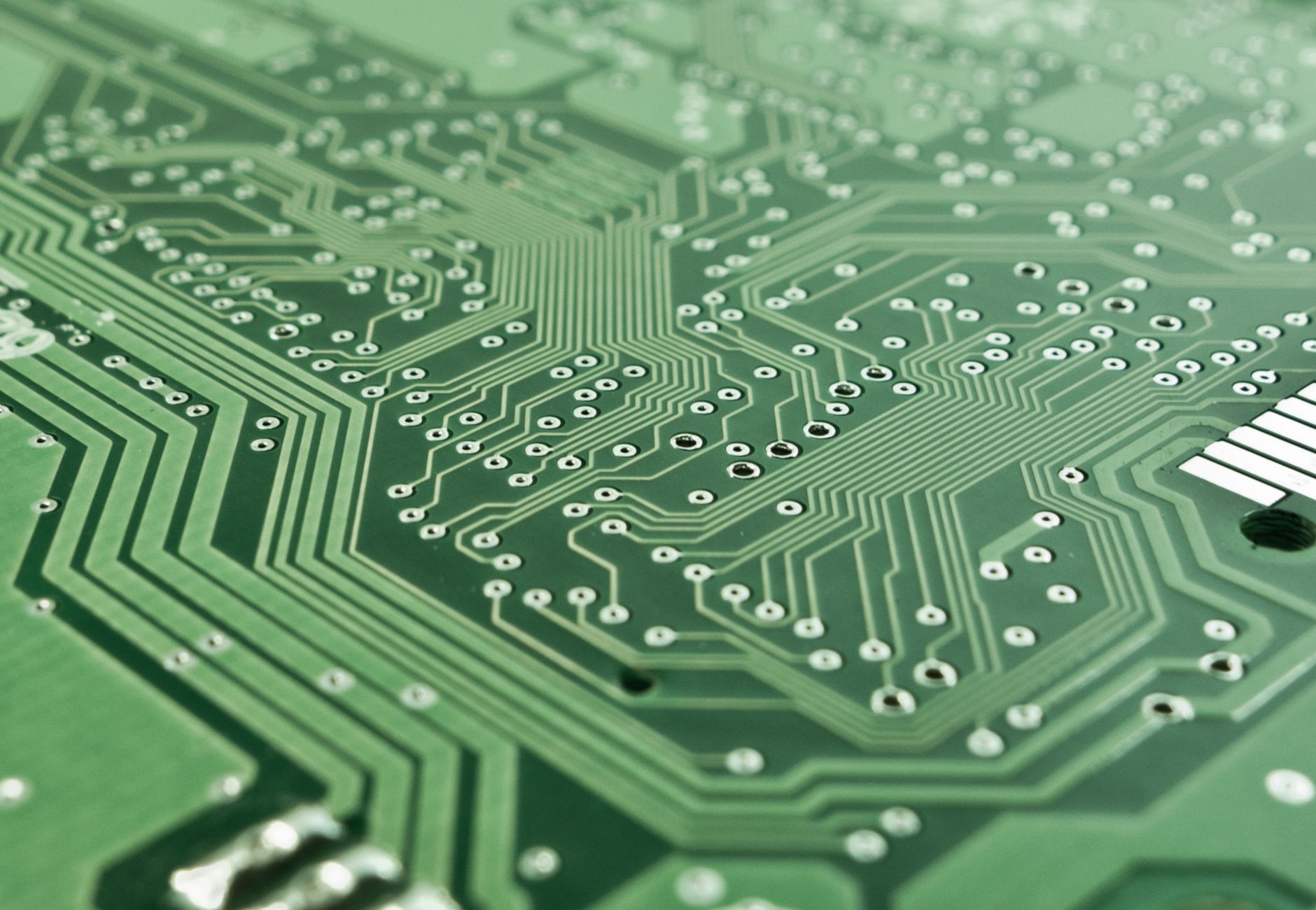 Detailed view of a green circuit board with complex patterns and pathways.