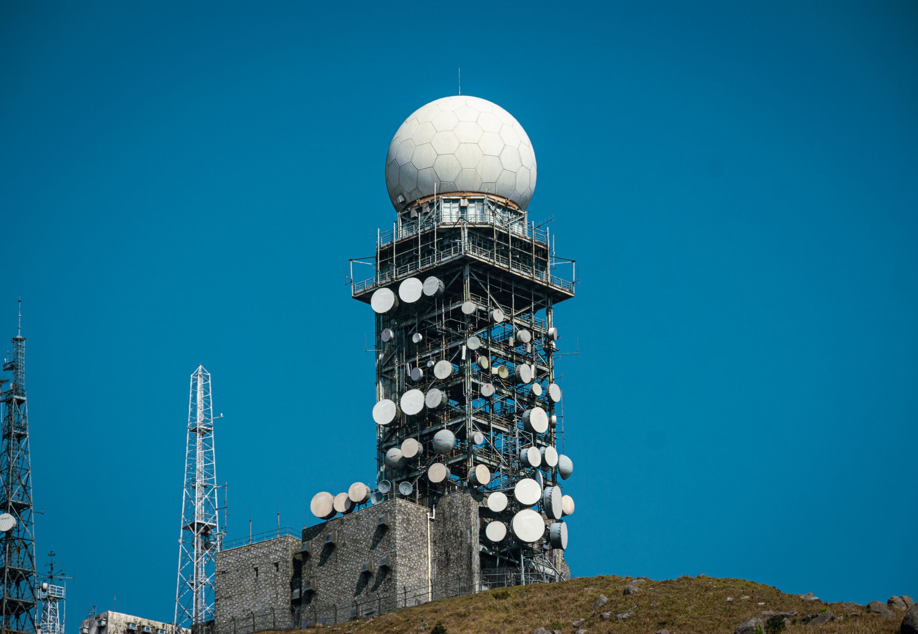 Imposing satellite tower with numerous dishes against a vibrant blue sky.