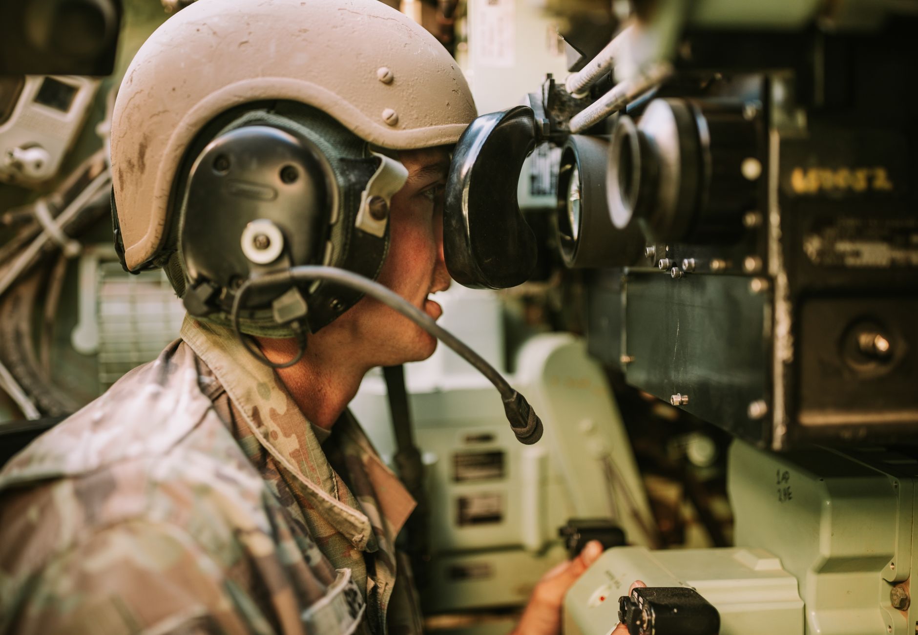 A soldier in uniform operates military equipment inside a vehicle, showcasing modern military technology.