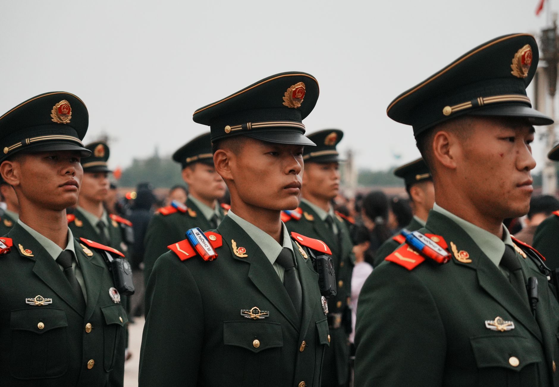 Close-up of military personnel in green uniforms and hats during a parade.